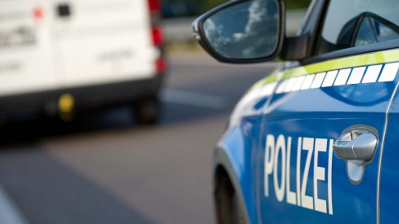 Polizeiauto im Vordergrund, weißer Lieferwagen auf der Straße im Hintergrund