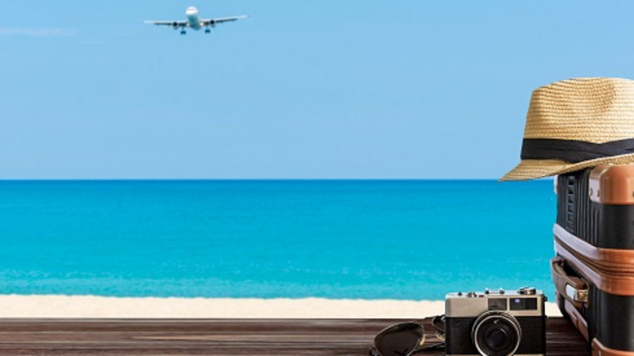 Flugzeug am Himmel und Koffer, Kamera, Sonnenhut am Meer