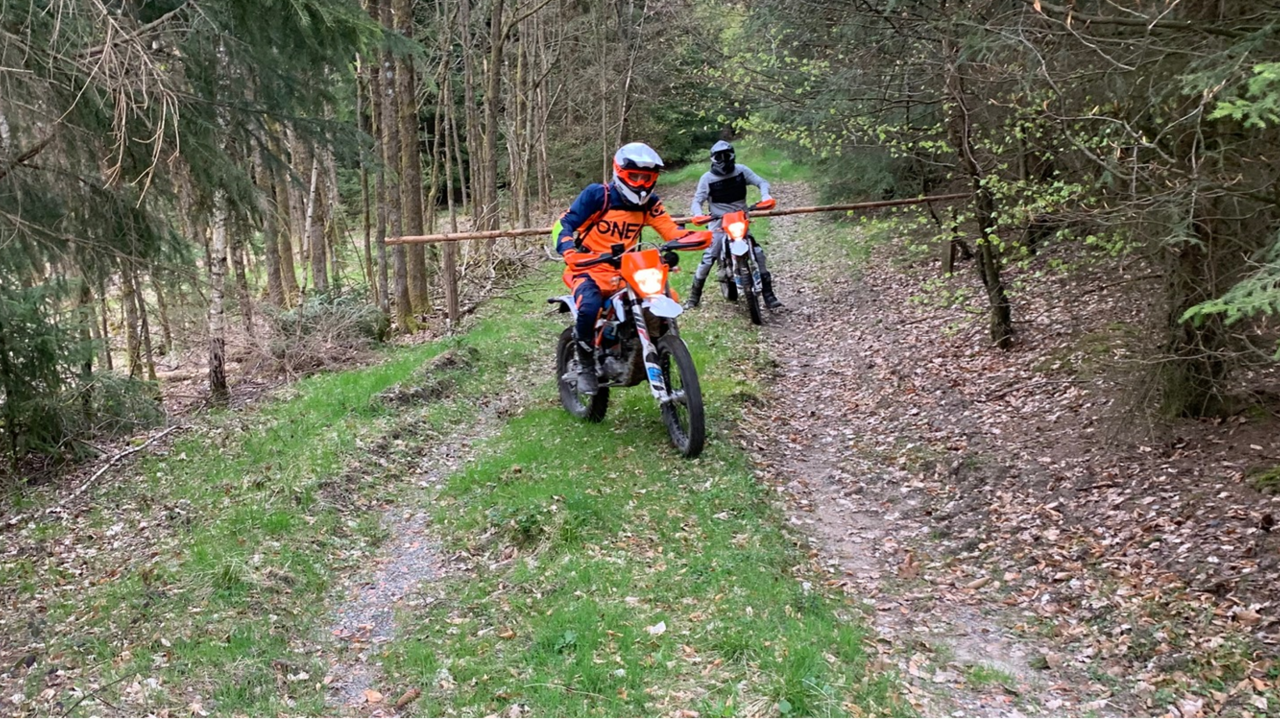 Ein unbekannter Motorradfahrer mit orangefarbenen Oberteil im Wald